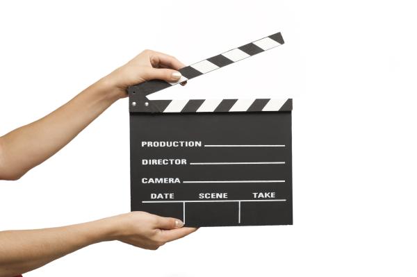 Blank movie or video clapperboard held by individual, with only hands and arms showing.