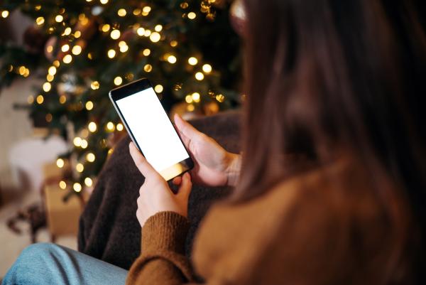 Woman using mobile phone sat next to Christmas tree
