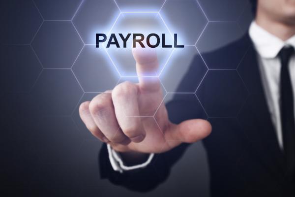 Man in suit pressing payroll icon which appears on virtual screen in front of him