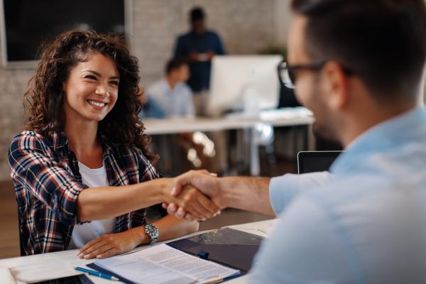 Young woman shaking hands with a man across a table