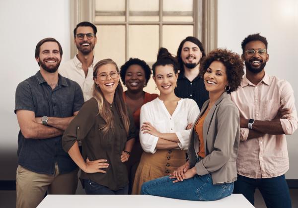 A group of people sitting or standing around a table looking happy