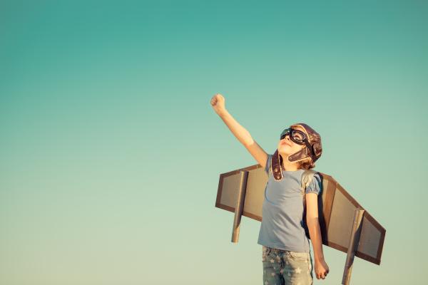 Child wearing toy wings and flying goggles