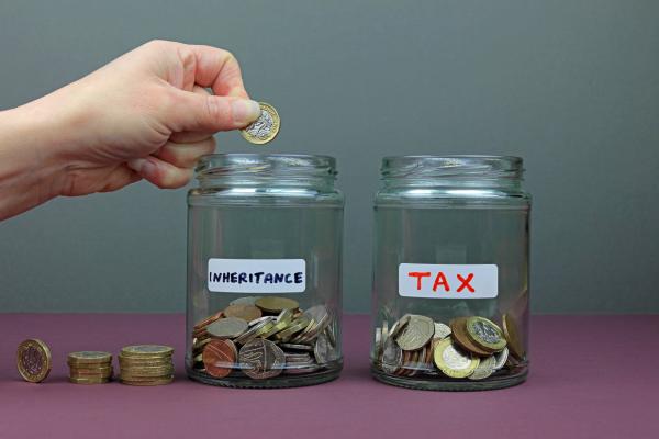 Two jars - the first labelled Inheritance, the second labelled Tax, both containing coins with a hand adding more coins to the first jar