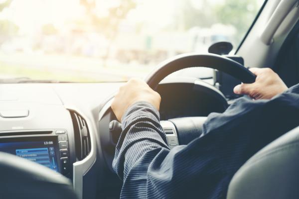 The hands of a man in a business suit are gripping the steering wheel of a car.