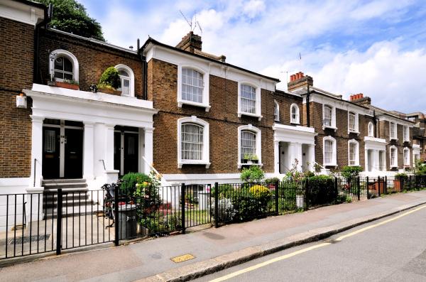 A view up a London street showing a row of Victorian brick houses with white painted window frames 