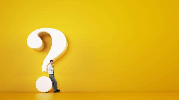 Man leaning against a large question mark and looking thoughtful