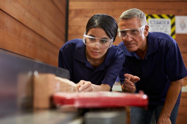 Apprentice being shown how to cut wood