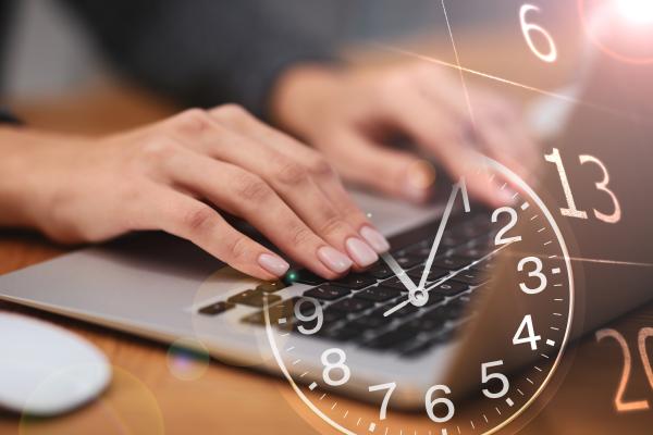 Hands using laptop with an image of an analogue clock overlayed