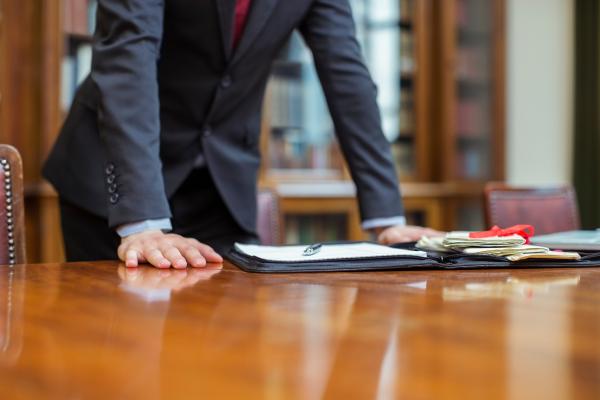 Man in suit leaning on table with documents infront of him