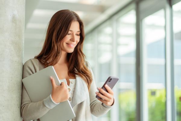 Smartly dressed woman smiling whilst using mobile phone