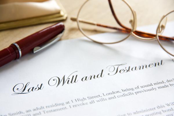 A pen and a pair of glasses are resting on the top of a document headed 'Last Will and Testament'