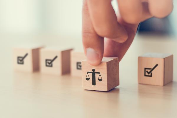 Hand picking up a wooden block showing an image of the scales of justice