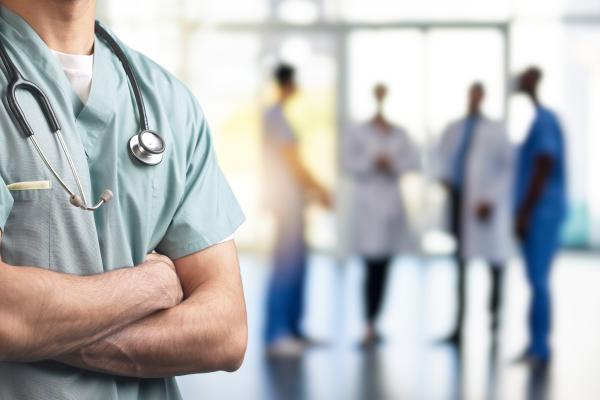 Medical professional in foreground with arms crossed, four more medical staff in blurred background