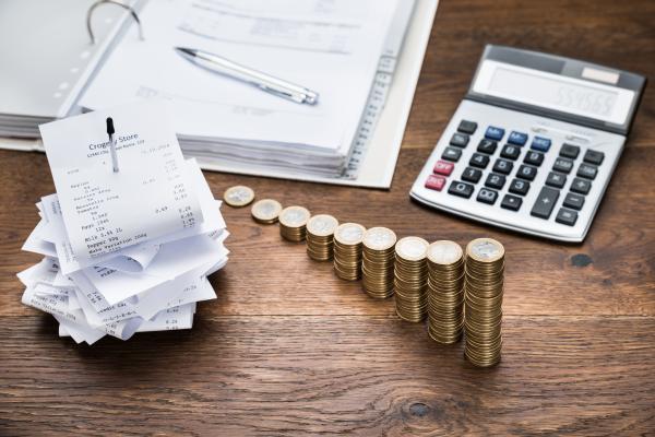 Desk with pile of receipts, ring binder file, calculator and piles of coins