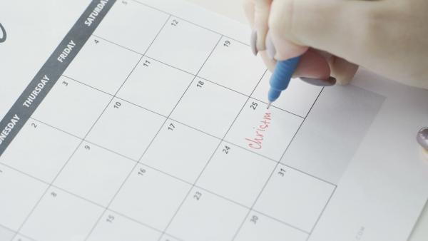 Close up of wall calendar with someone writing "Christmas" on number 25 