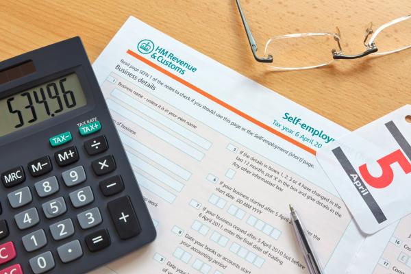 Pages of a Self-Assessment tax return on a desk with calculator and pen