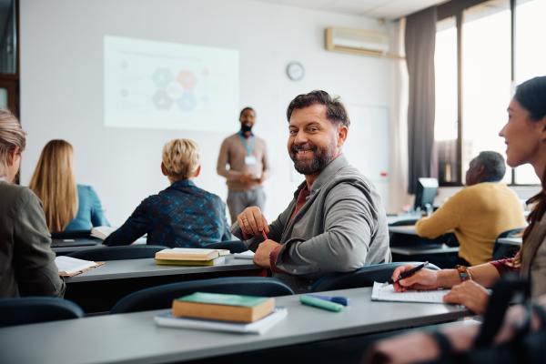 Classroom setting with one attendee turning backwards to smile at the camera