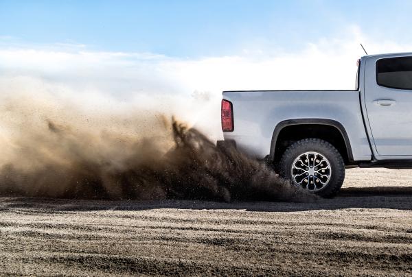 Back end of a double cab pickup truck driving on a sandy surface