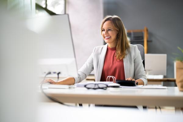 Smartly dressed woman sat at a desk using a computer