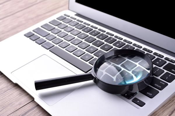 Laptop on a desk with a magnifying glass on top of it